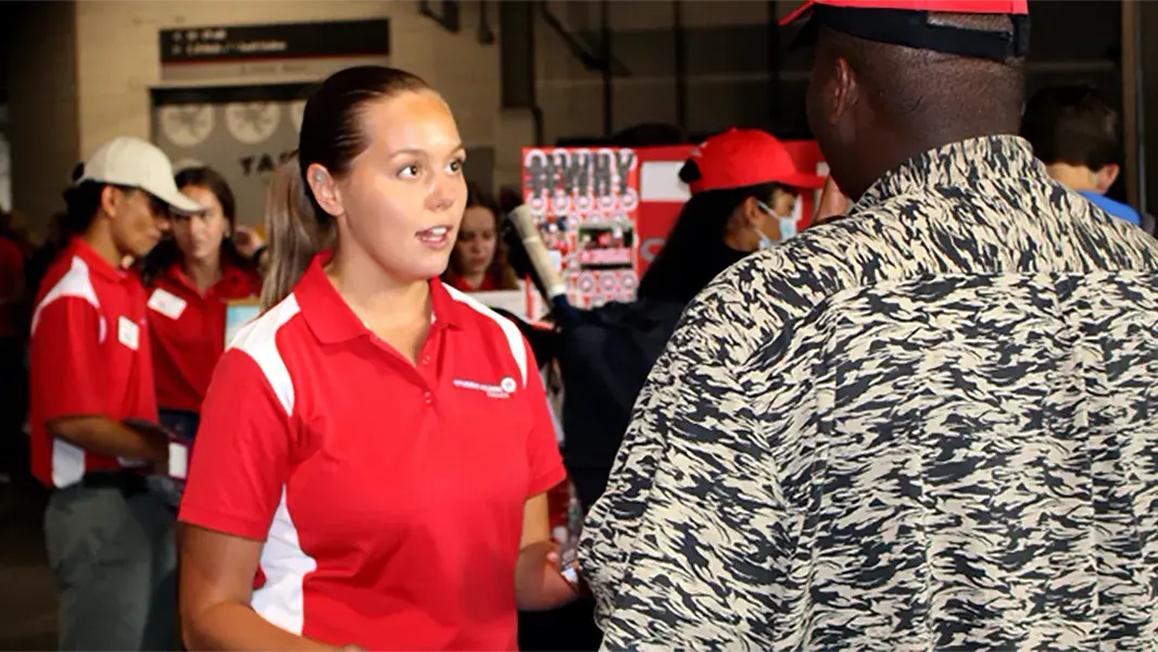 woman wearing ohio state red polo engages with a man during a recruiting event