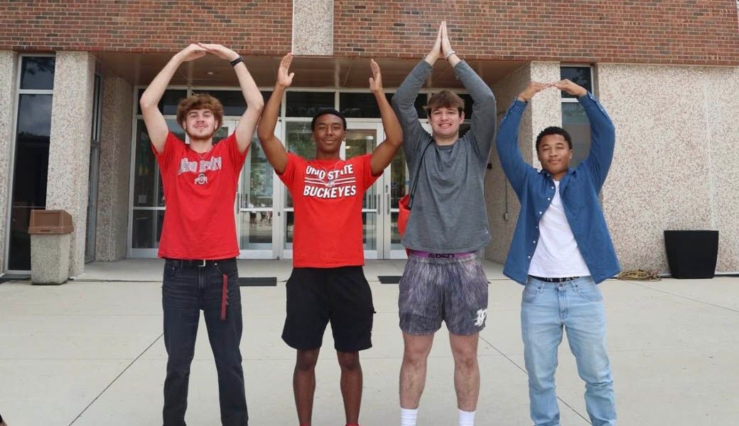 Four students do O-H-I-O on the Ohio State campus
