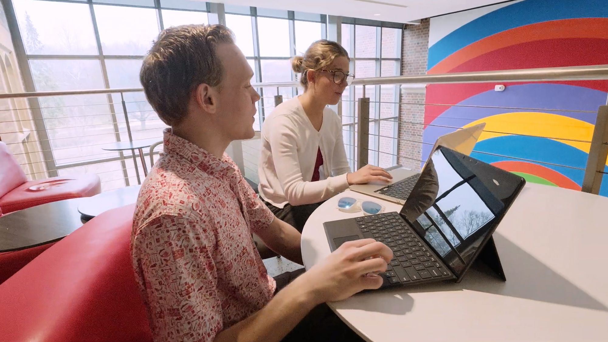 A student works on a laptop while seated next to another student