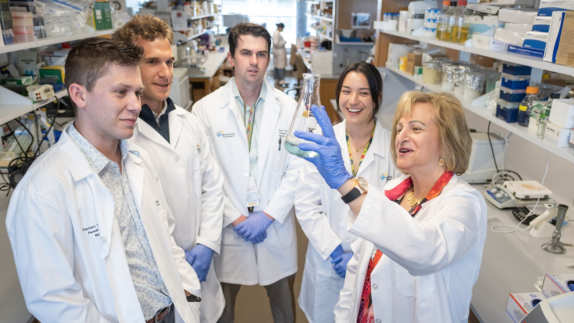 A group of five researchers examine a container of fluid