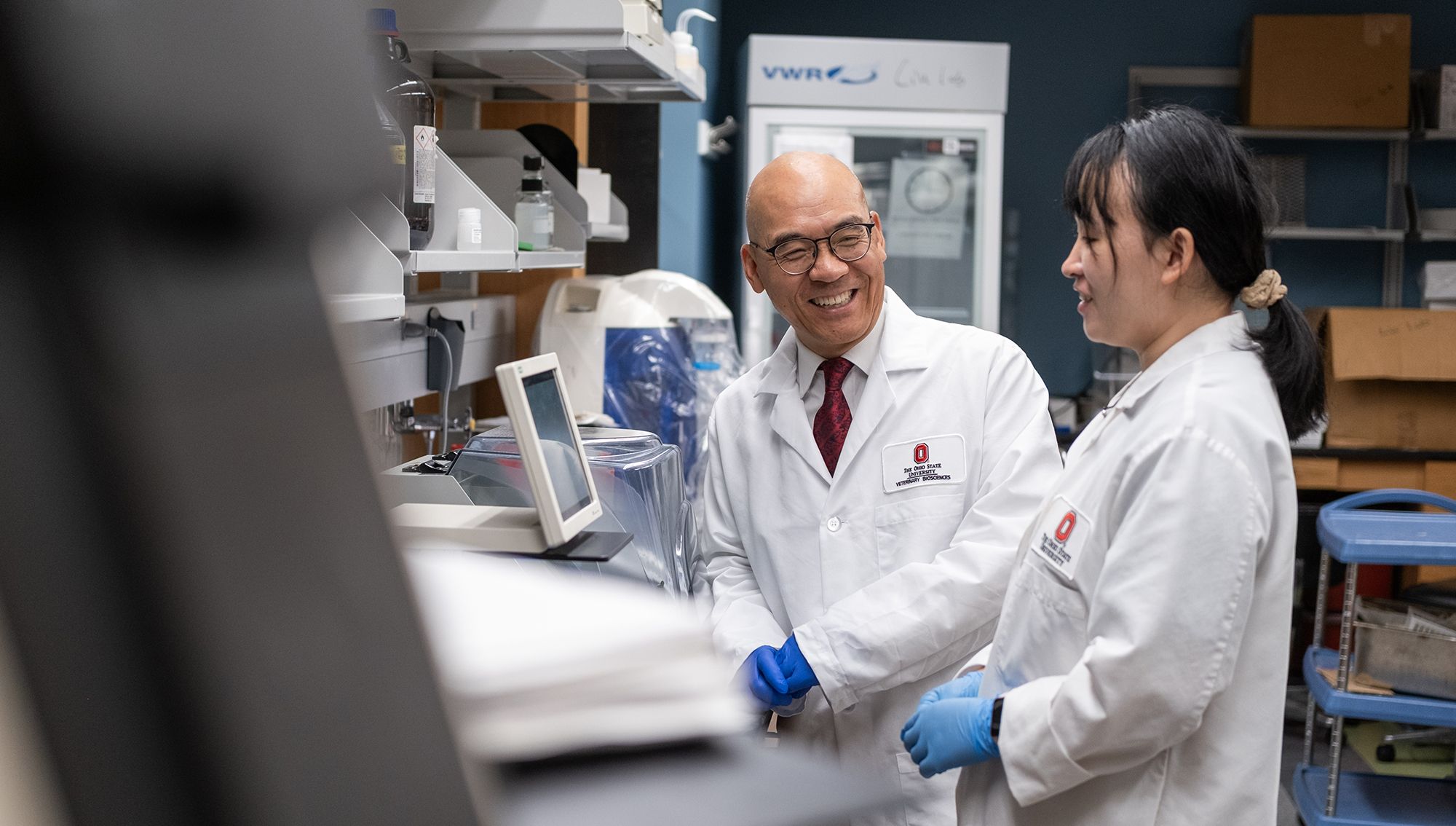 A researcher looks and smiles at a fellow researcher as they work on a project together.