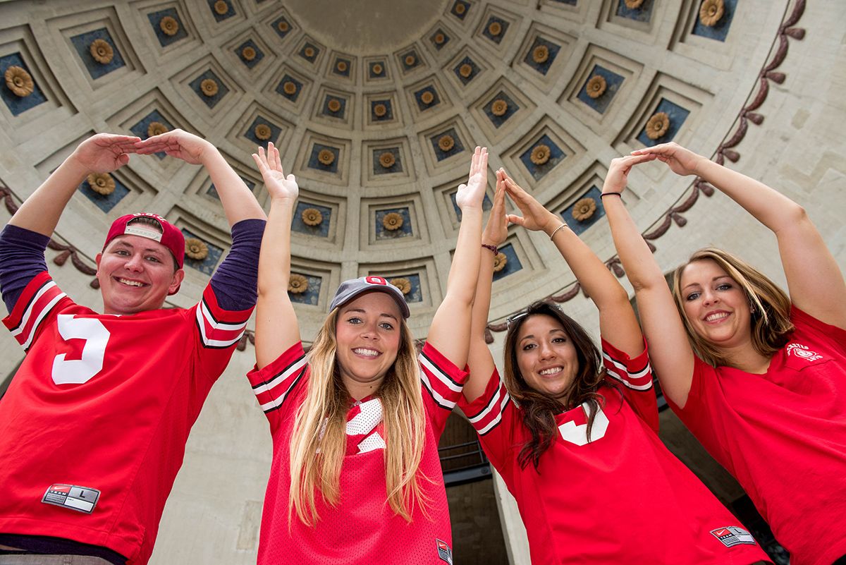 Four students in Ohio State football jerseys perform O-H-I-O in the Ohio Stadium rotunda.