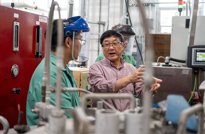 Alan Luo works in his lab while speaking with a colleague.