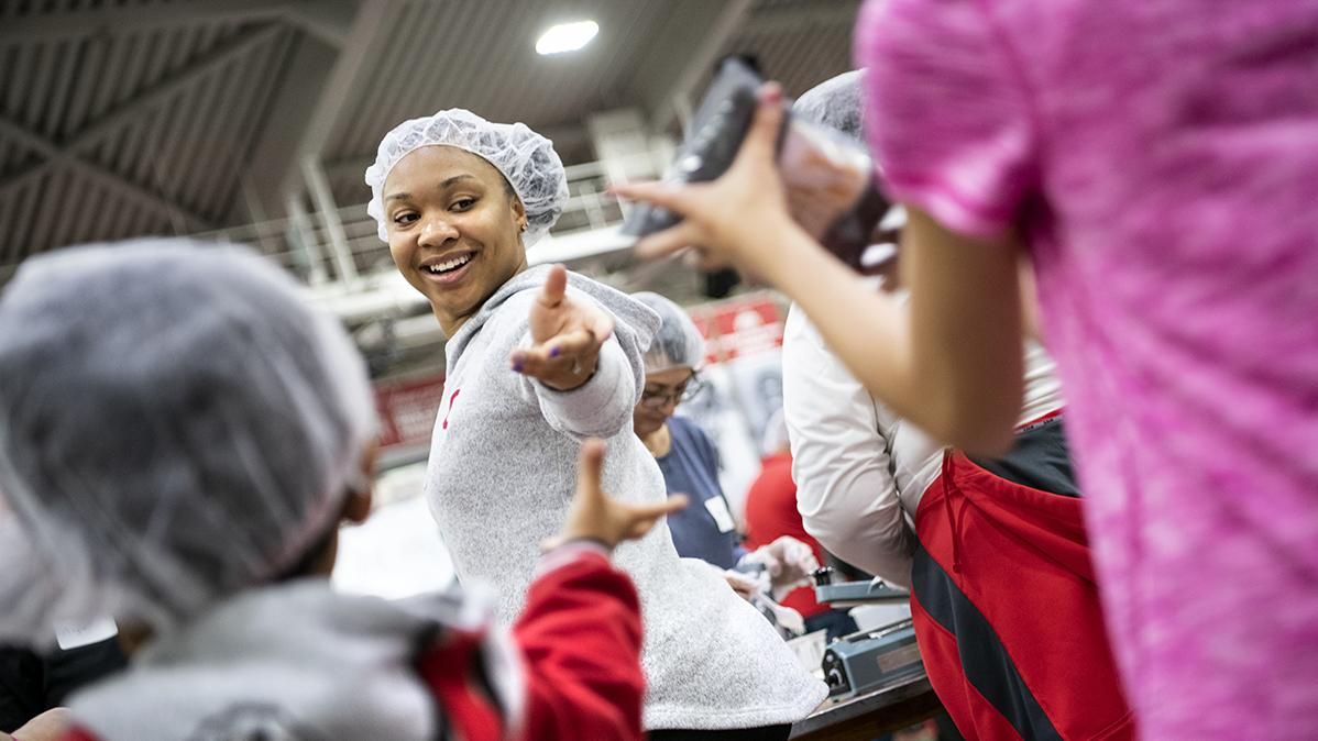 A community member wearing a hairnet works in a food pantry