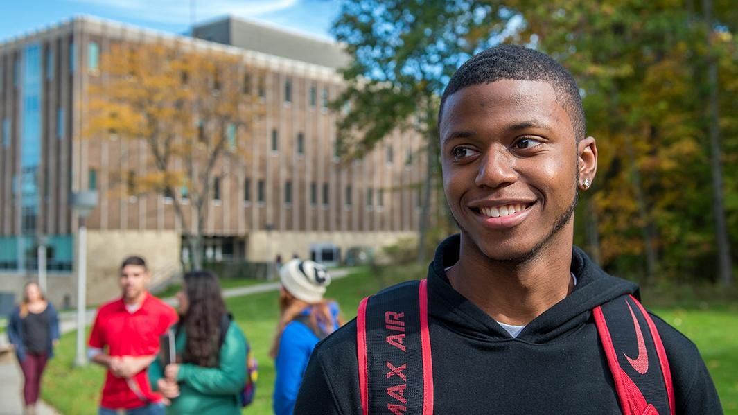 A student smiles while other students congregate behind him