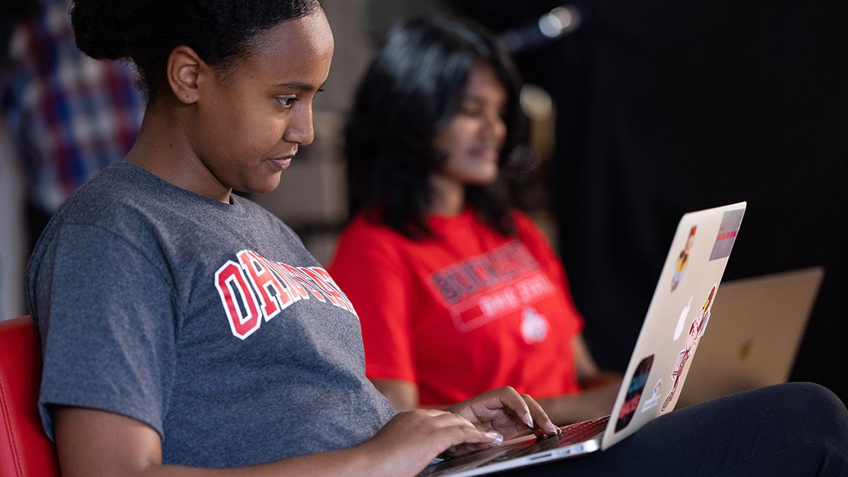 Two students work on laptop computers.