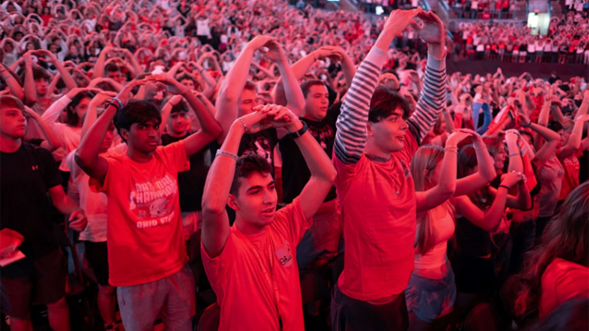 Students hold their arms up in an O shape at Convocation