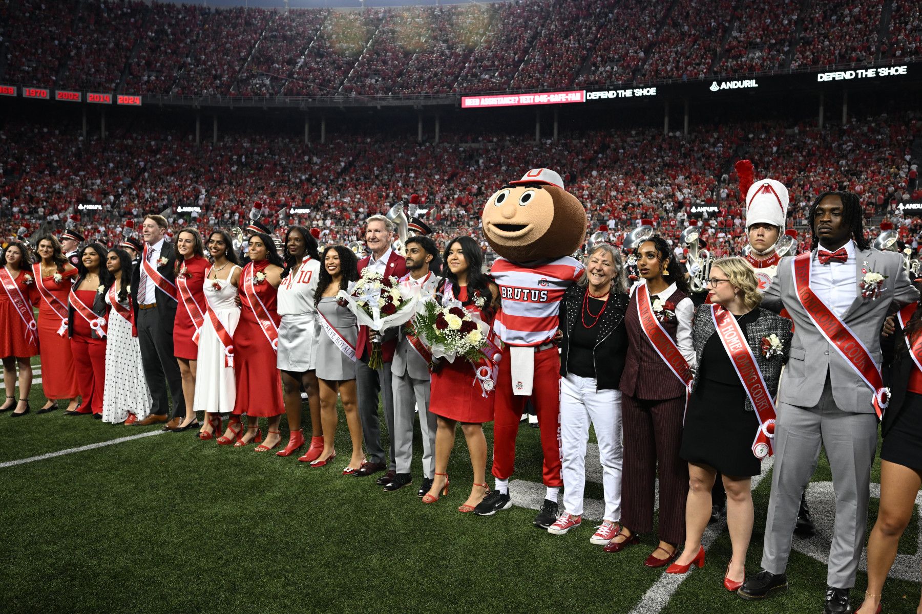 2025 Homecoming Court arm-in-arm on the football field