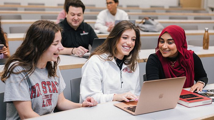 Three women smiling and looking at a laptop