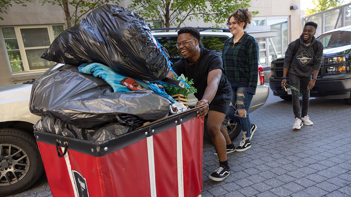 A student pushes a red cart filled with bags and boxes during Move-In day at Ohio State