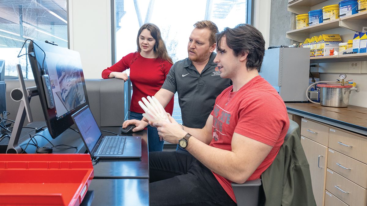 Three Ohio State researchers interact while reviewing data on a laptop computer