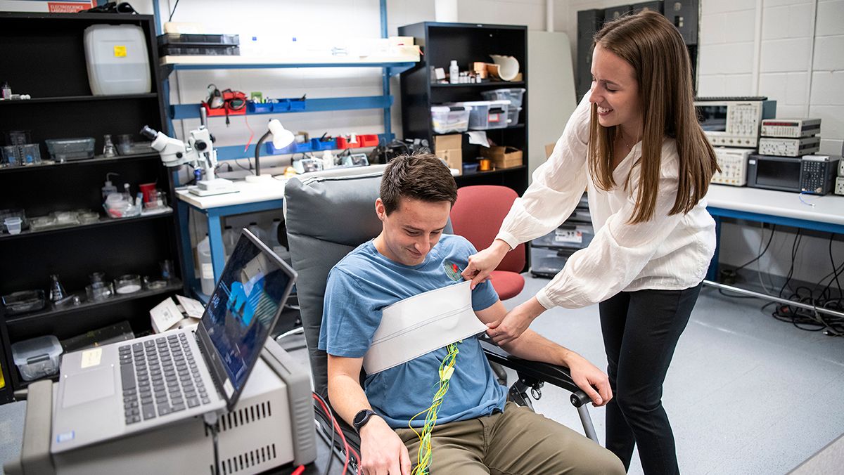 Ohio State student Ally Rice applies sensors to a student seated in a chair in a lab