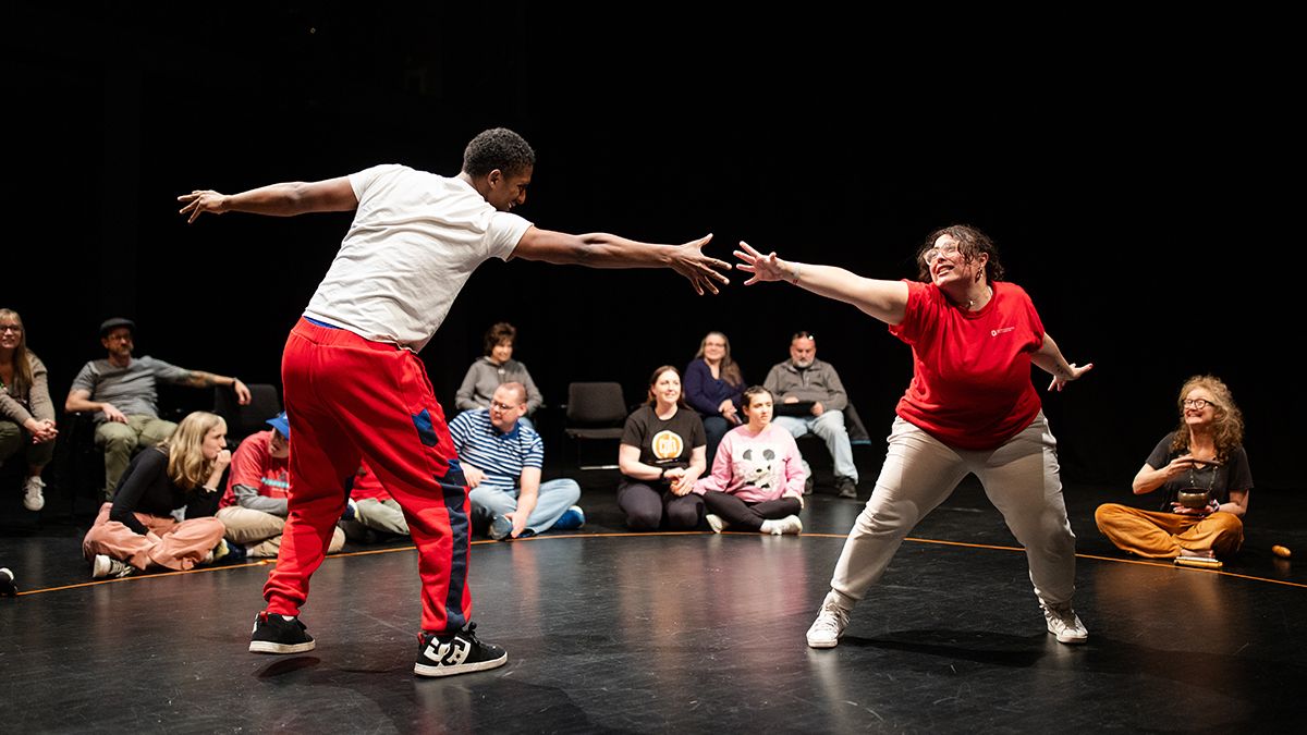 Two performers touch hands during an event featuring Ohio State's Shakespeare and Autism program.