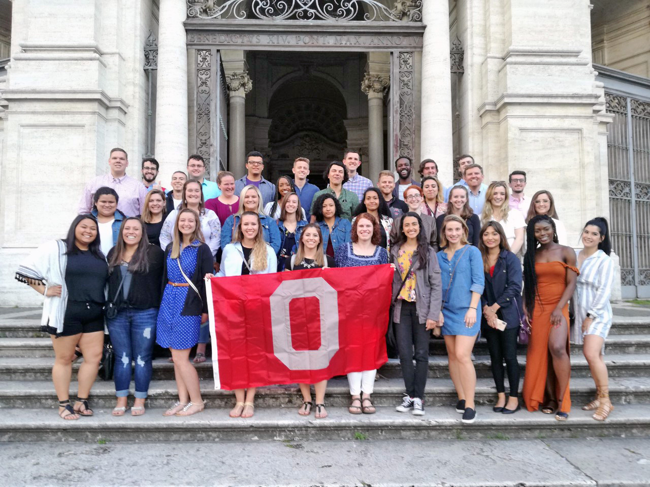 Osu alumni in Europe posing with an OSU flag