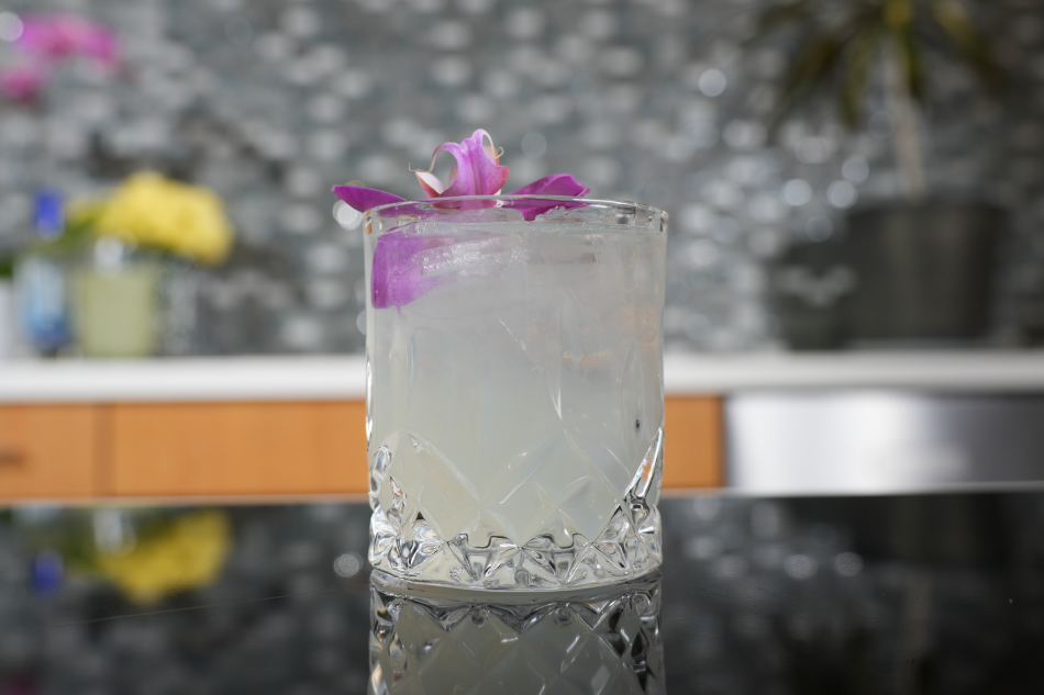 clear cocktail with orchid garnish