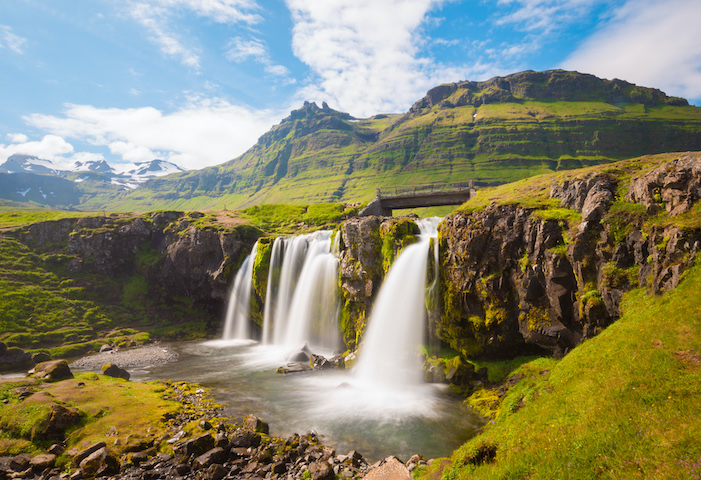 Several waterfalls on side of a lush green mountain