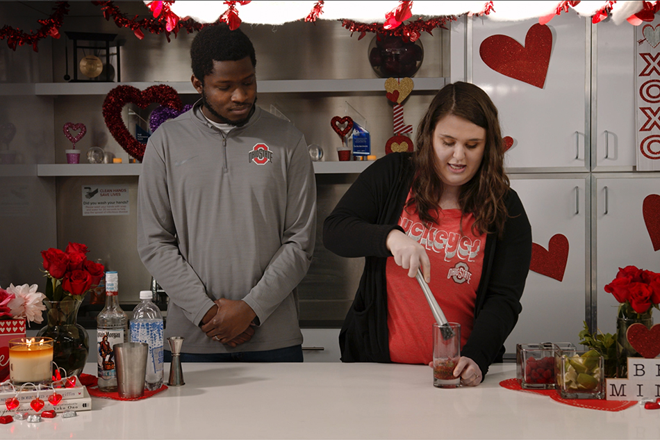 a couple mixes a drink together