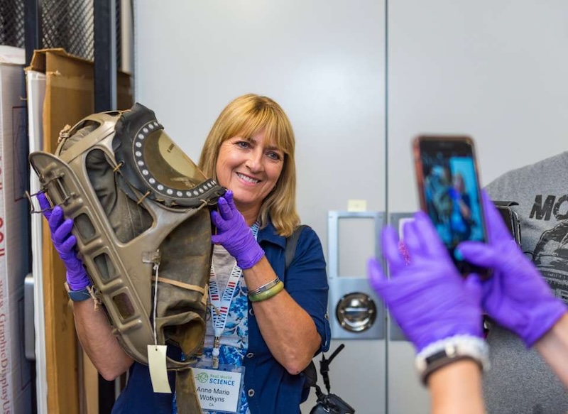 A lady holding equipment and wearing purple gloves