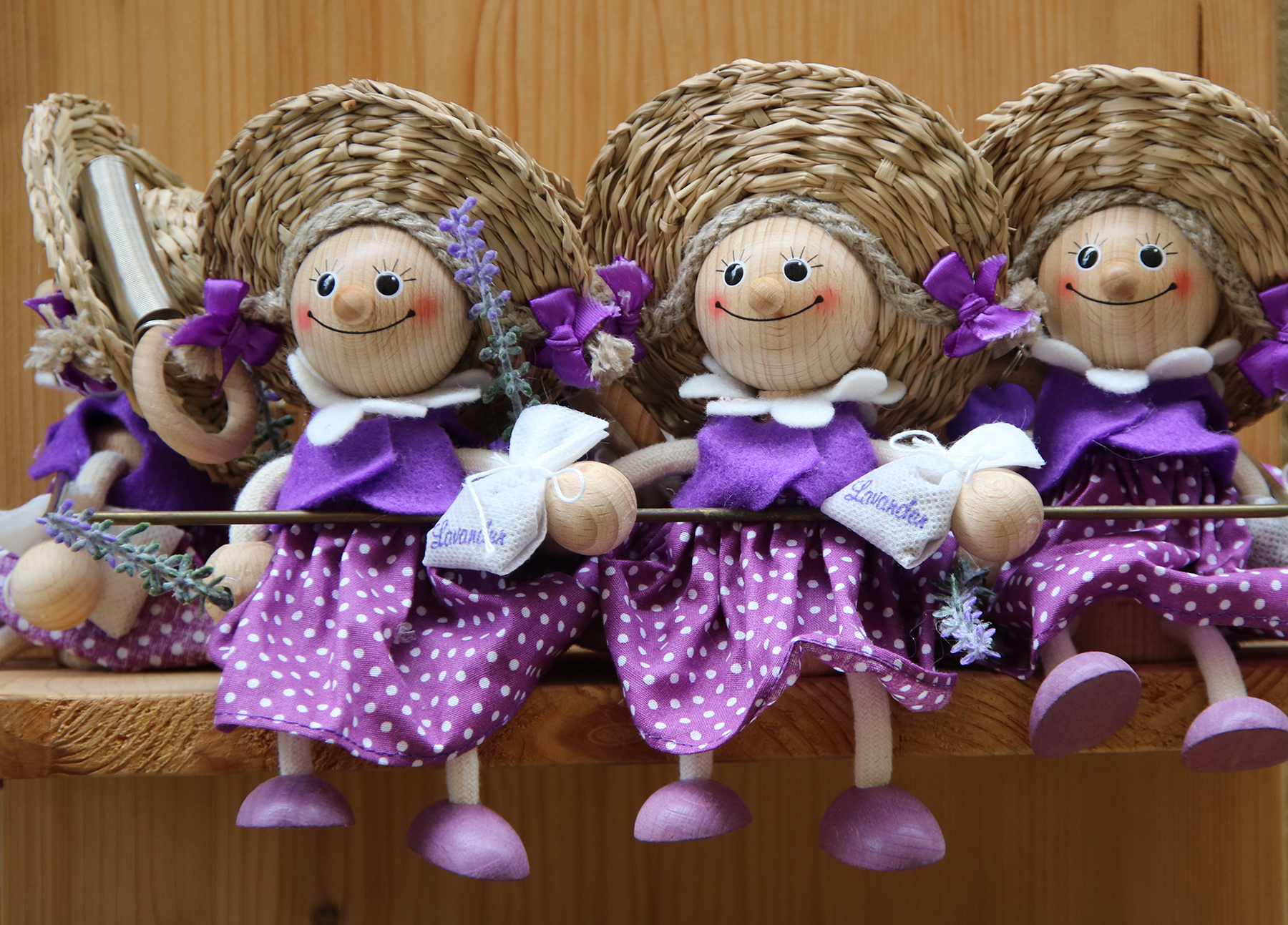 Three dolls in purple dresses and straw hats