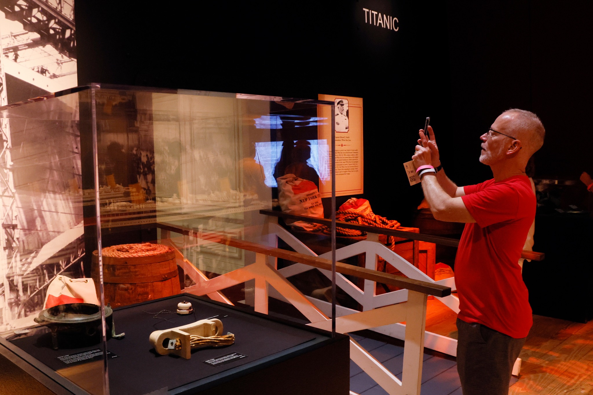 A man wearing a red shirt takes a picture of a museum exhibit