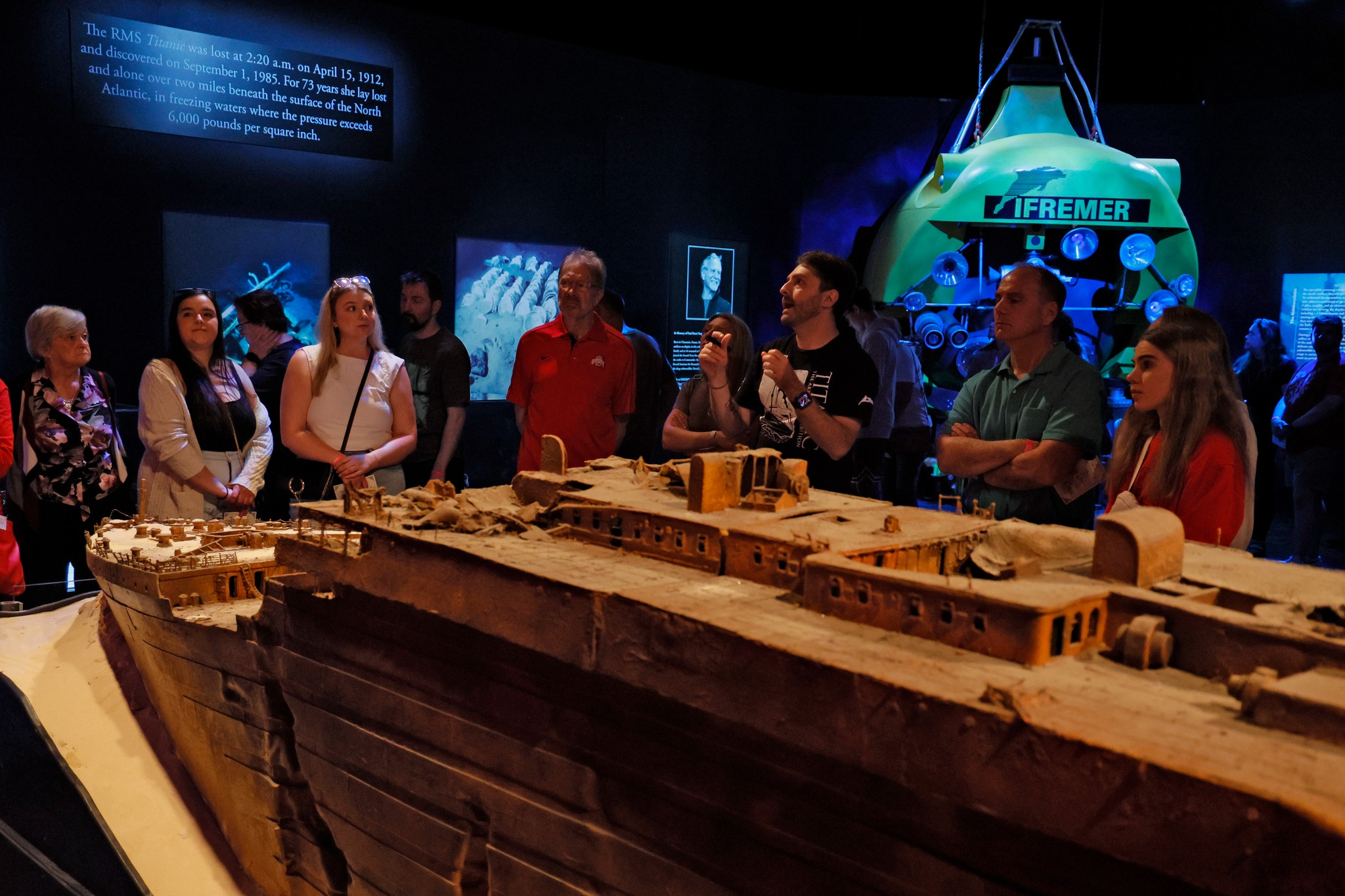 group of seven people standing around a model display of the Titanic