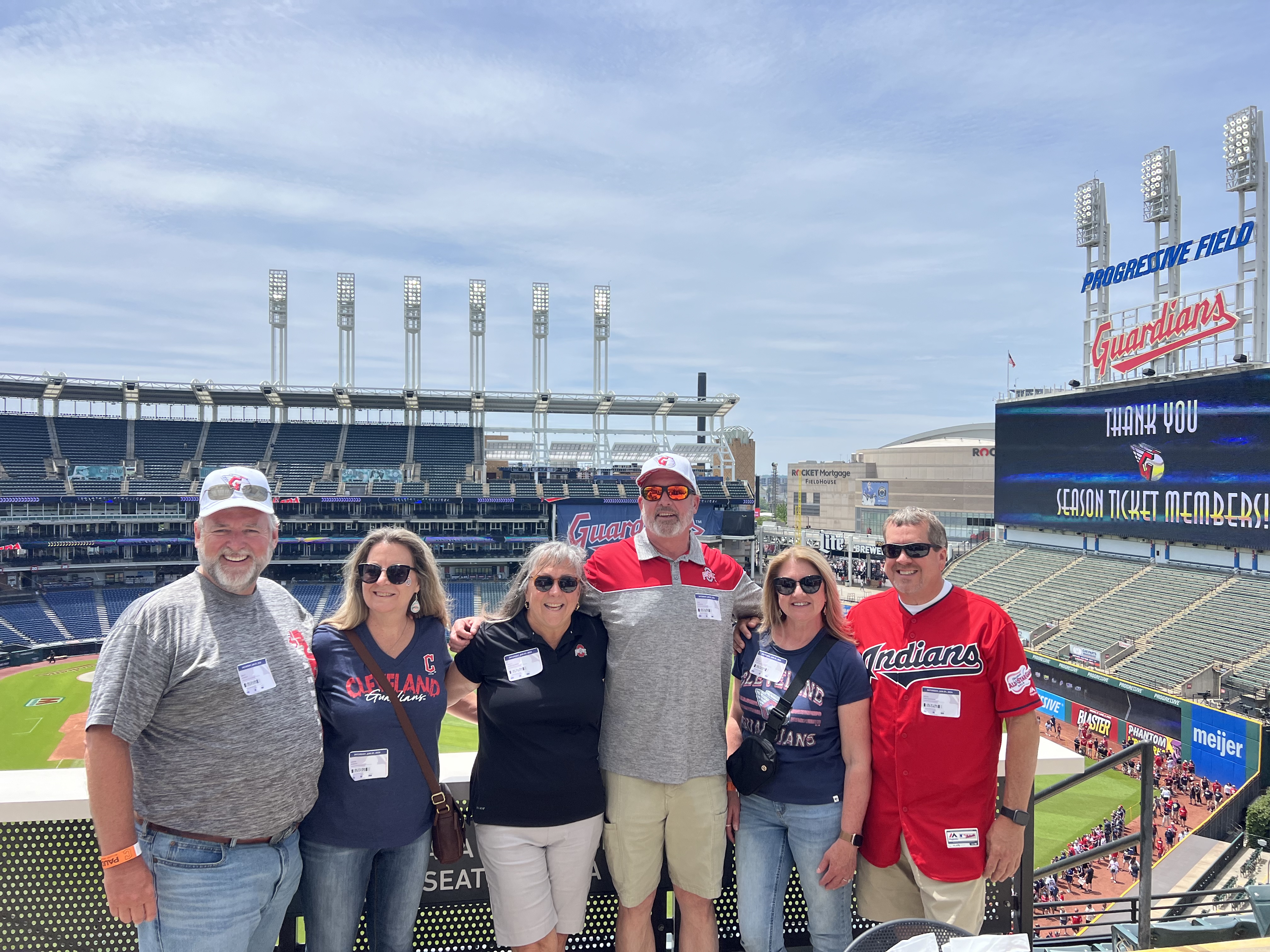 six adults standing with a baseball stadium in the background