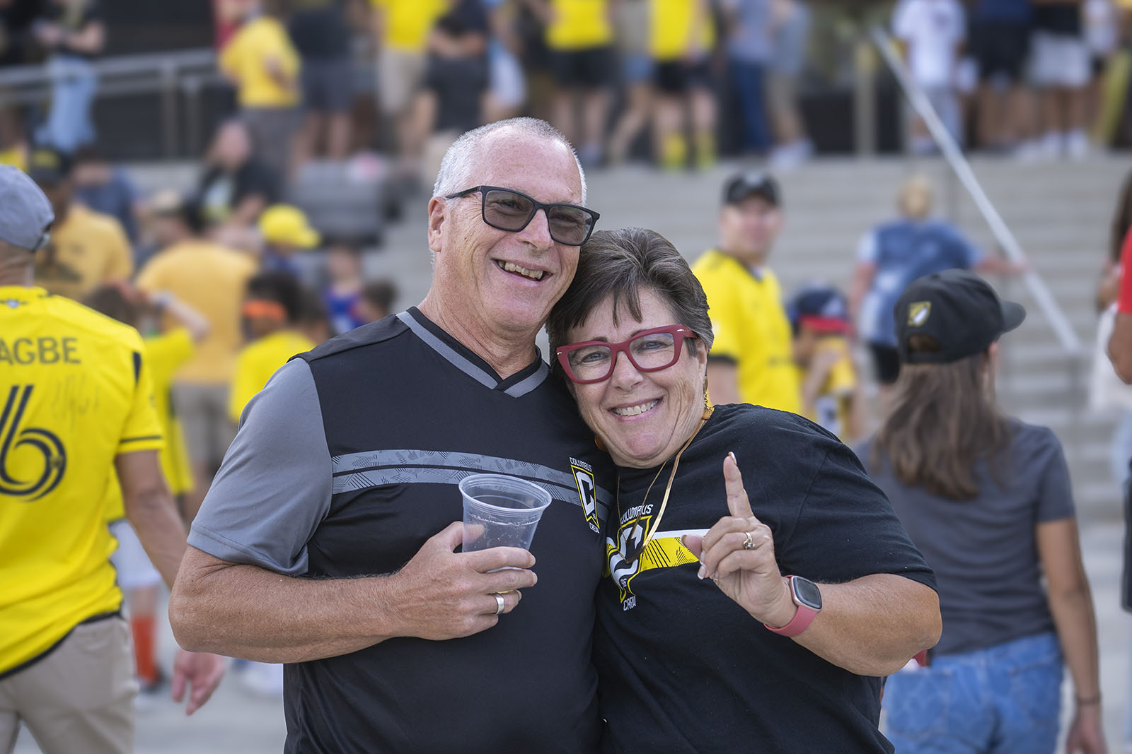 two people wearing Columbus Crew shirts smile together