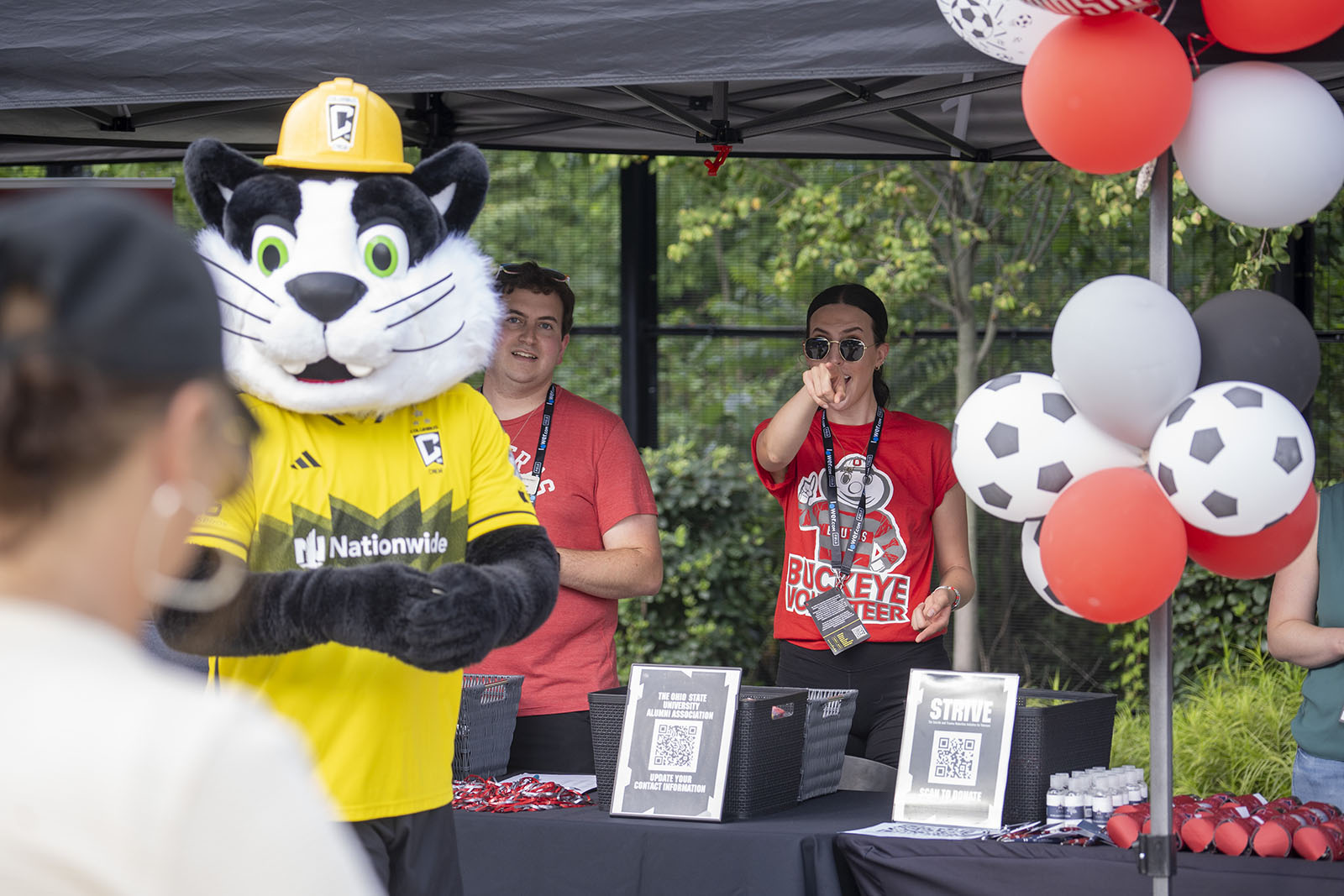 An Ohio State staff member points playfully while standing people an event registration table