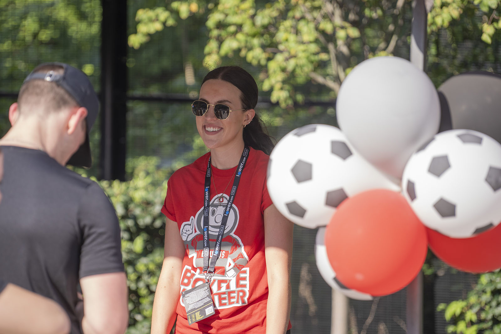 a smiling person wearing black sunglasses and a red Brutus Buckeye T-shirt