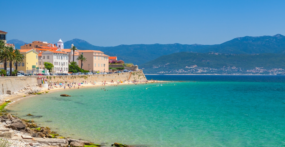 a turquoise beach with buildings along the shore