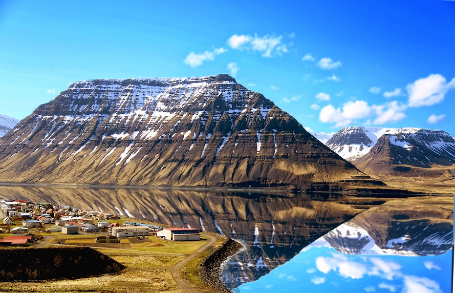a large peak sitting beside a calm body of water