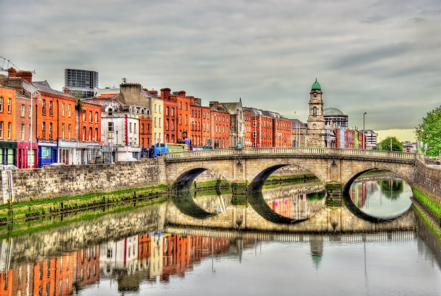 Bridge over a calm channel with a row of buildings lining the bank in Dublin
