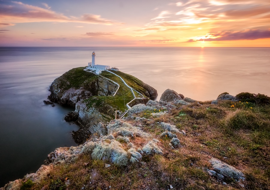 A lighthouse overlooking the ocean at sunset in Holyhead