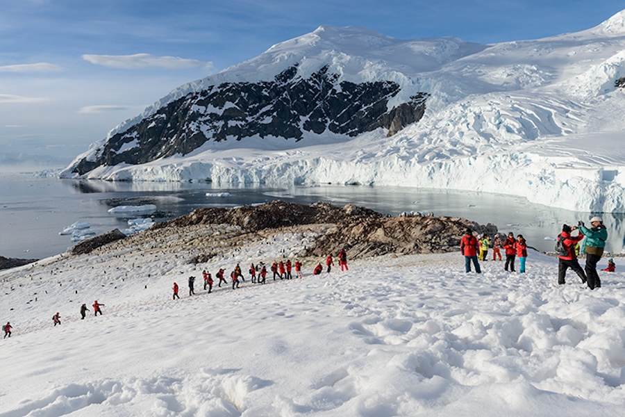 A large group of travelers hiking on a glacier
