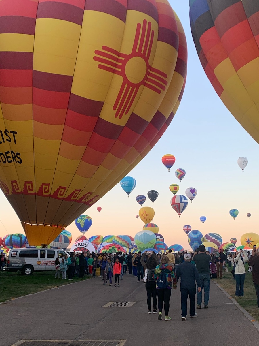 people walking through hot air balloons on the ground