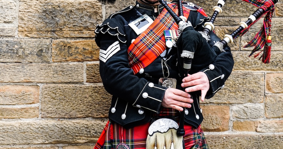 A man playing the bagpipes and wearing traditional Scottish attire