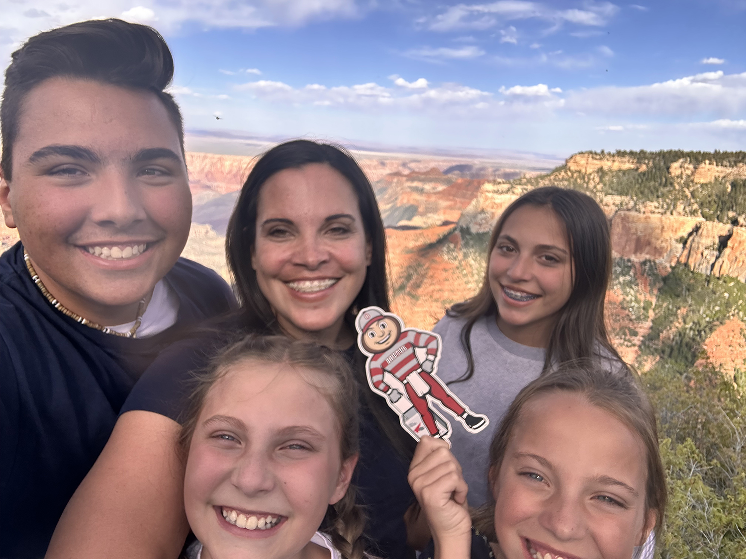 A woman with one young man, and three young ladies, holding Brutus, in front of the Grand Canyon, Arizona.