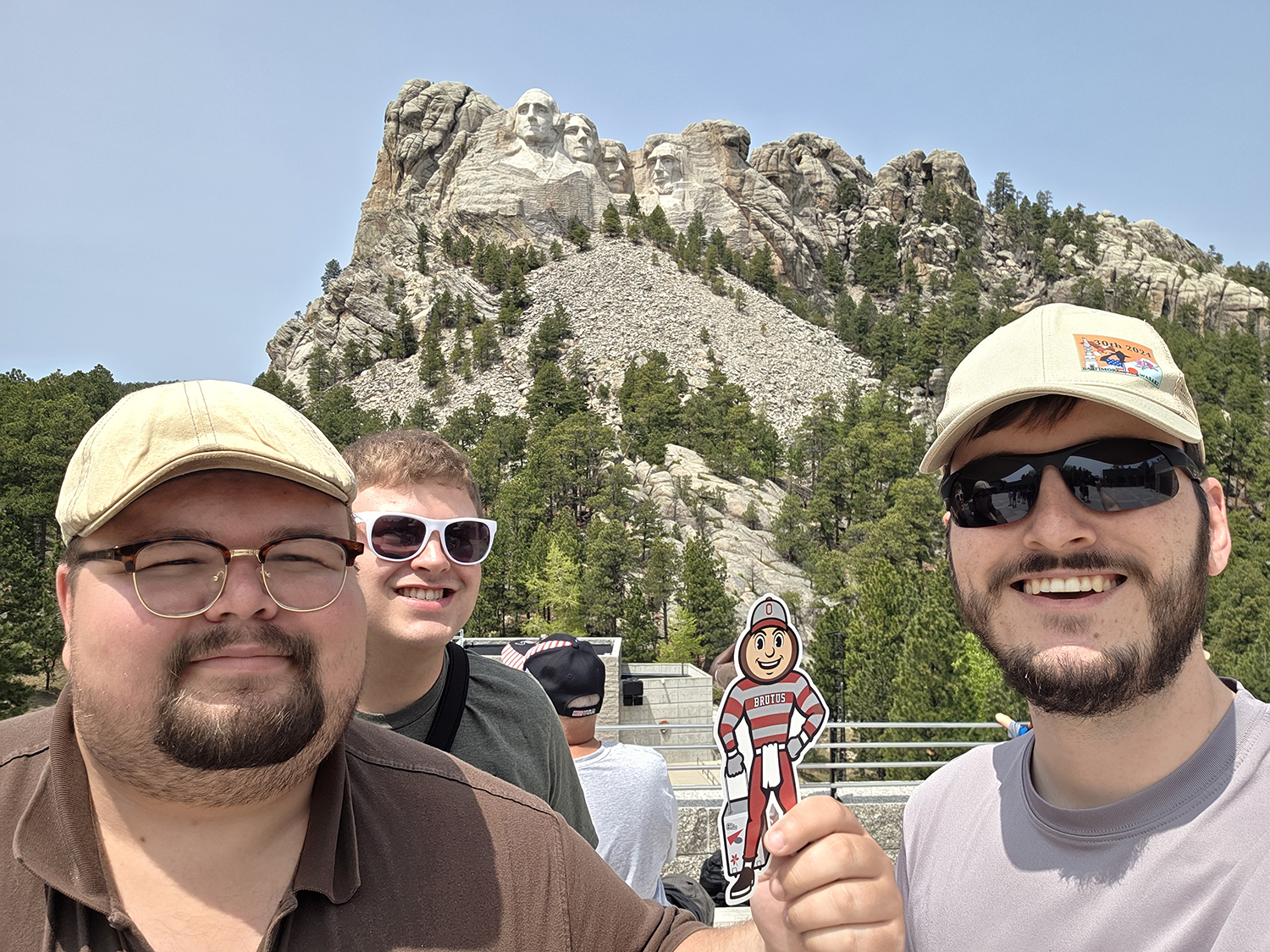Brutus with three men in front of the Mount Rushmore monument in South Dakota.