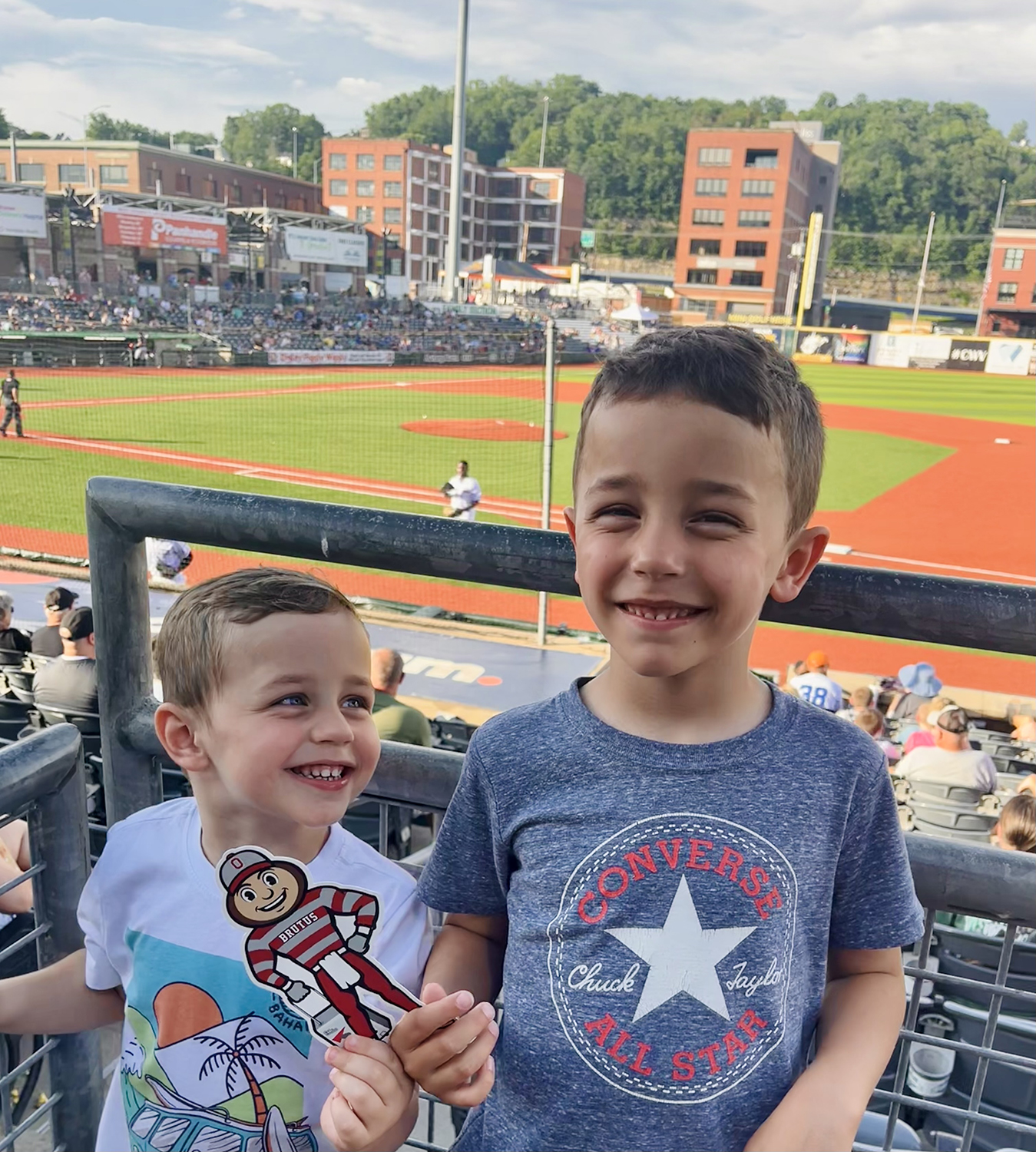 Two boys holding Brutus with a baseball game going on in background in Charleston, West Virginia.