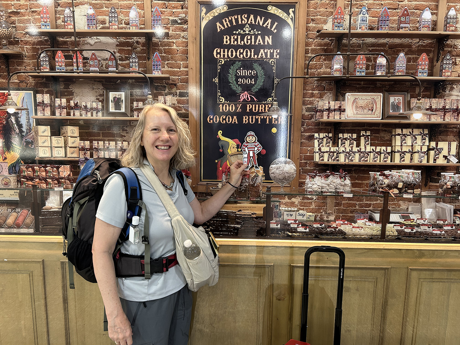 A woman holding Brutus in front of a large assortment of Belgian chocolate in a store in Brussels, Belgium.