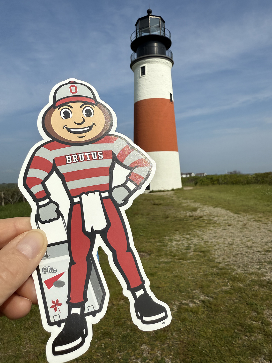 Brutus in front of a white and red striped lighthouse in Sconset, Massachusetts.