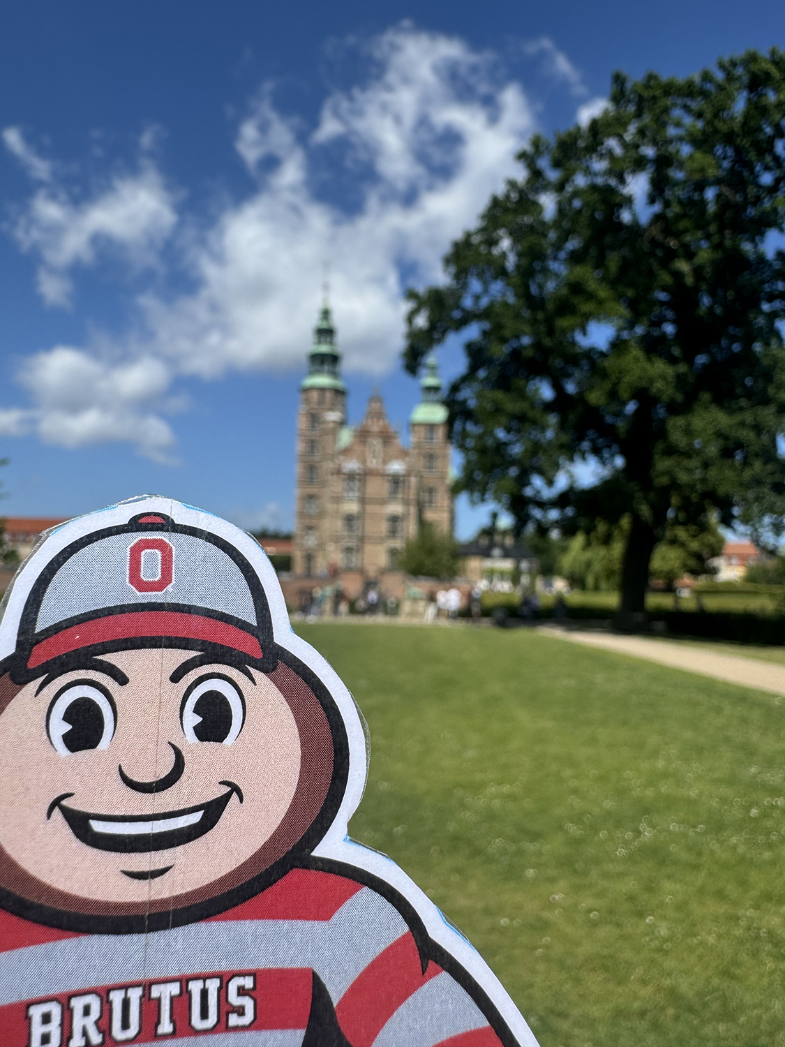 Brutus in front of Rosenborg Castle in Copenhagen, Denmark, on a sunny day with blue skies and white wispy clouds.