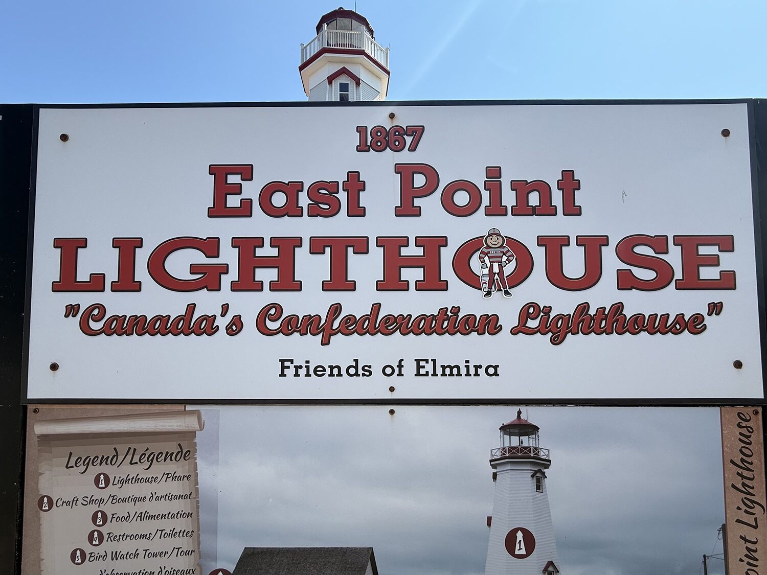 Brutus on a sign reading 1867 East Point Lighthouse Canada's Confederation Lighthouse Friends of Elmira on Prince Edward Island, Canada.