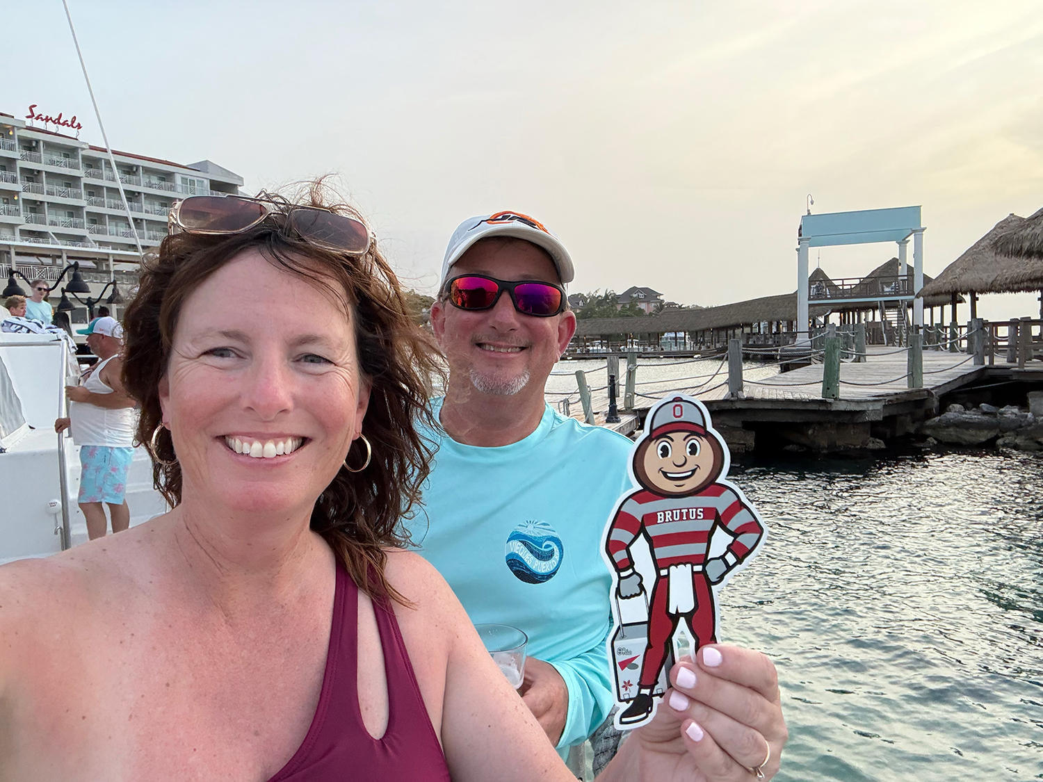 Brutus being held by a woman with a man behind her, both smiling, standing on a dock in Ocho Rios, Jamaica.