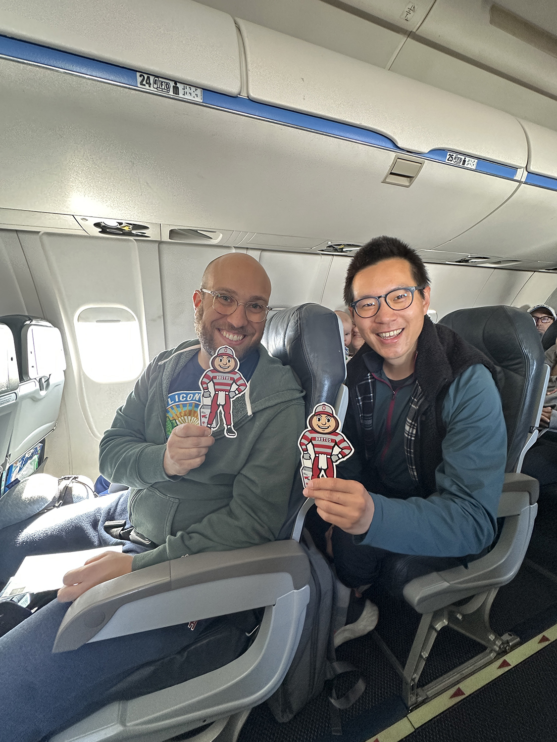 Two men on a plane, both holding Brutus, in Toronto, Canada.