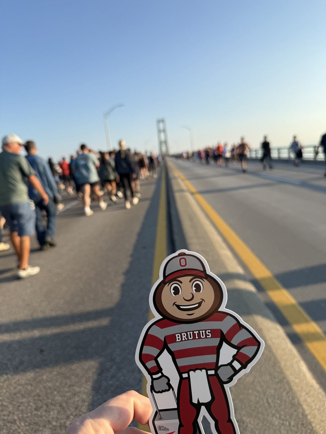 People walking on a bridge in Michigan with Brutus Buckeye cutout in foreground.