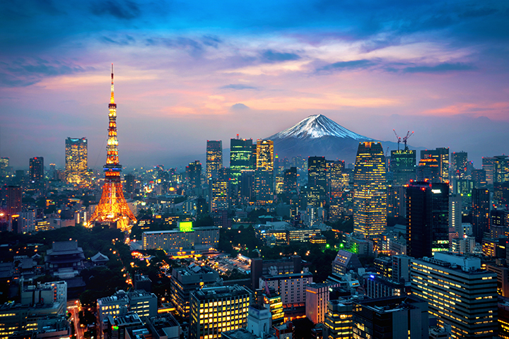 Tokyo’s skyline at dusk with a glowing tower and Mount Fuji in the distance.