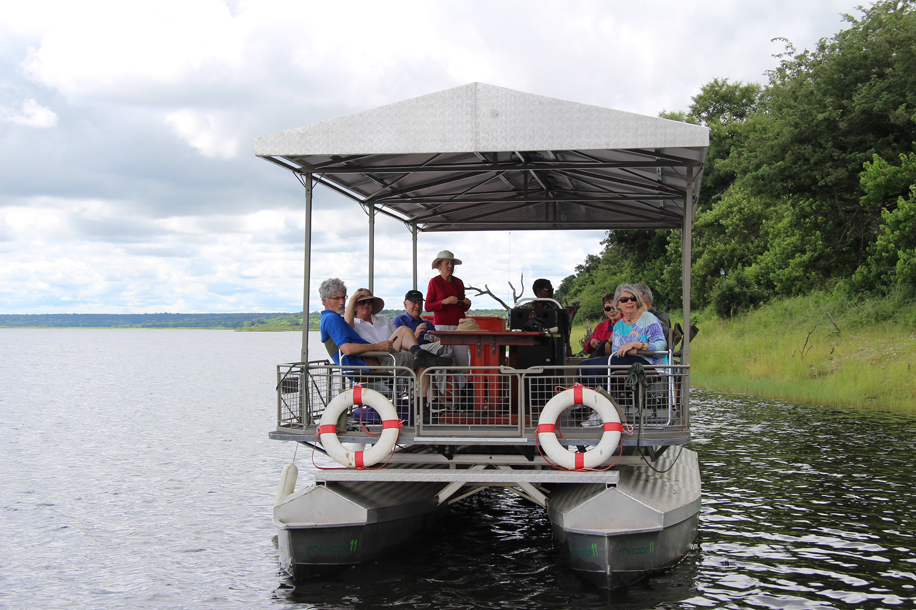 Pontoon boat with passengers touring on a calm river.