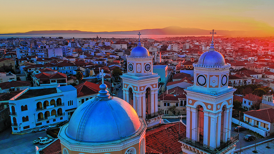 Cityscape at sunset with blue-domed towers in the foreground and buildings stretching toward the horizon.