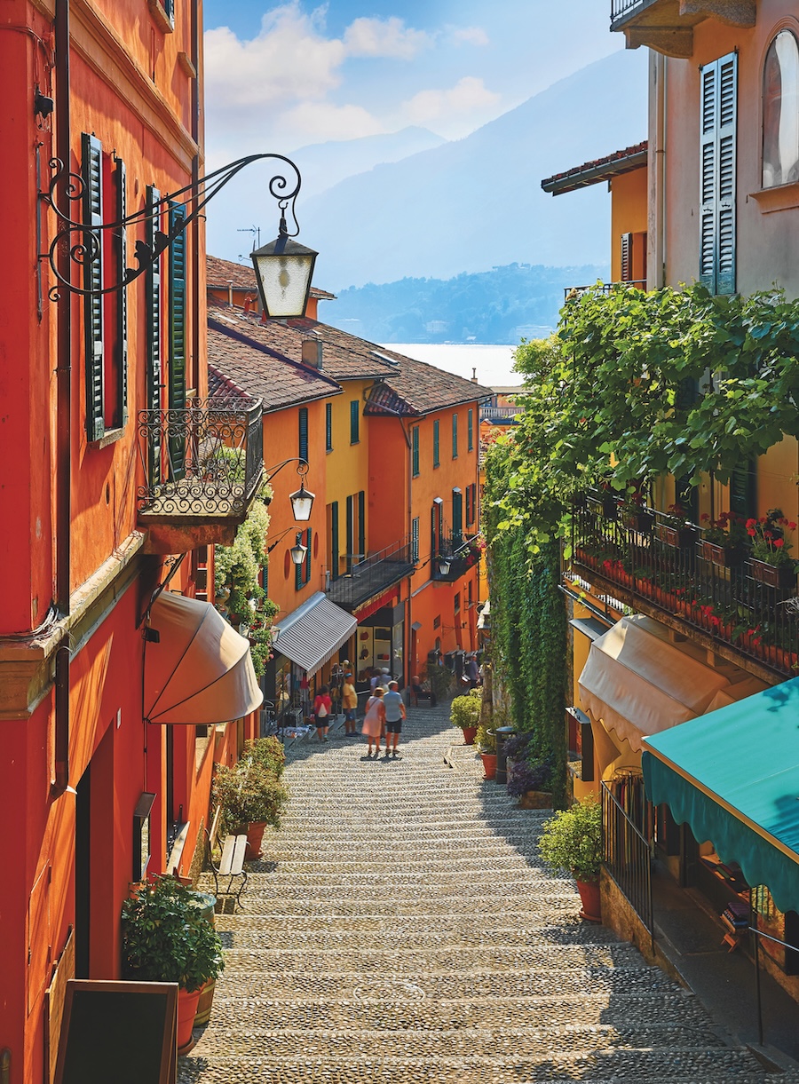 A narrow city street with bright orange shops lining each side in Bellagio